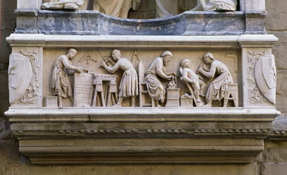 Relief, das Künstler und Handwerker bei der Arbeit darstellt, vom Sockel der Nische, die die Quattro Coronati darstellt